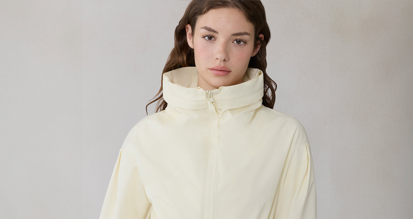 Woman wearing a light-colored jacket against a plain background